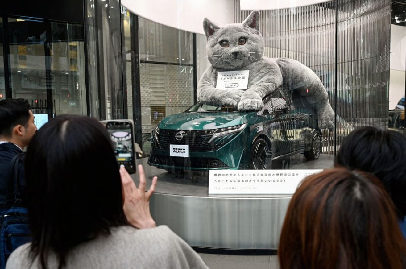 Nissan Japan использовал необычный маркетинговый ход, разместив трёхметрового кота рядом с новой моделью Aura в выставочном зале